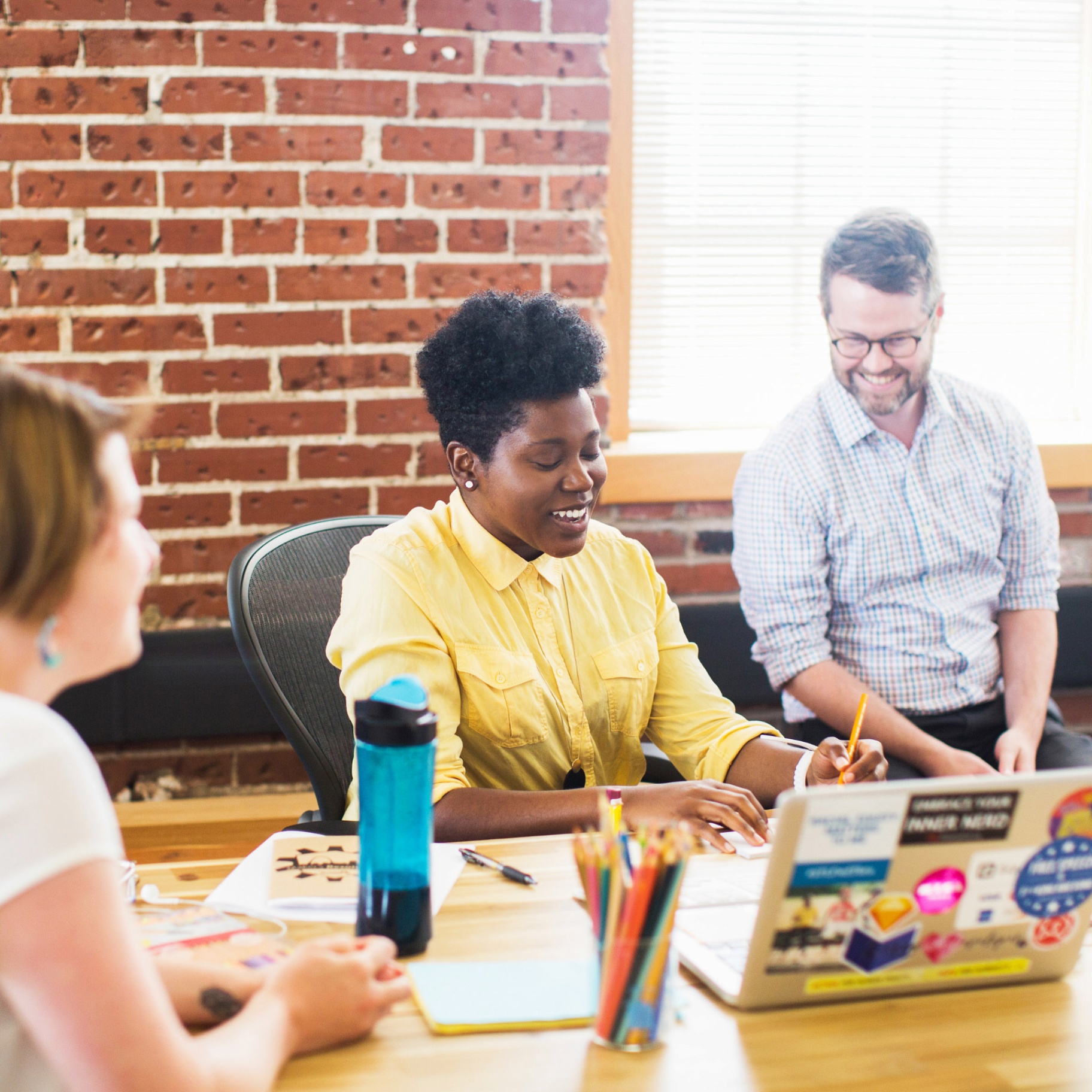 CIC members collaborating at a desk by a brick wall